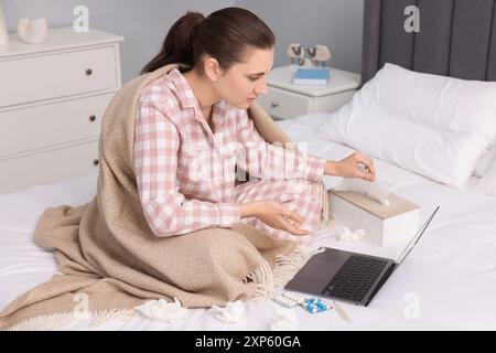 Sick woman having online consultation with doctor via laptop at home Stock Photo