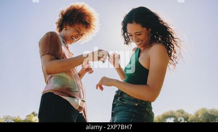 Young best friends having fun outdoors, sharing laughter and joy under a clear blue sky. Enjoying moments of happiness and connection. Stock Photo