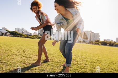 Two friends dancing together in an open park after school for social media content. Girlfriends having fun and enjoying the summer sunshine and doing Stock Photo