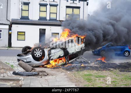 A car burns after being overturned during an anti-immigration protest in Middlesbrough. Picture date: Sunday August 4, 2024. Stock Photo