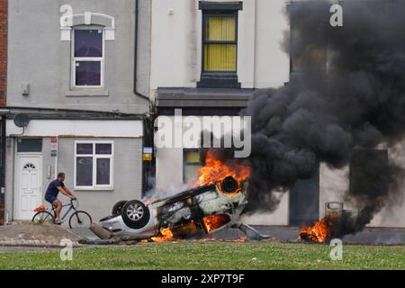 A car burns after being overturned during an anti-immigration protest in Middlesbrough. Picture date: Sunday August 4, 2024. Stock Photo
