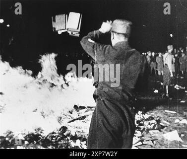 Book burning in Berlin, May 10, 1933.  A member of the SA throws confiscated books into the bonfire during the public burning of 'un-German' books on the Opernplatz in Berlin. Stock Photo