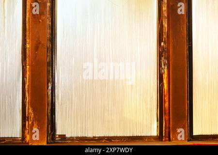 Window with a wooden frame and a dirty glass pane. The glass pane is covered in a pattern of lines Stock Photo