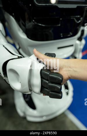 A woman shaking hands with a robot Stock Photo