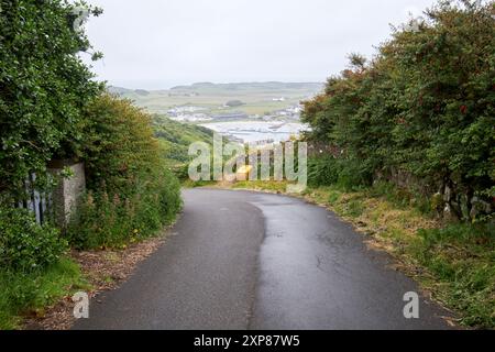 narrow steep country road leading down to church bay in rain rathlin island, county antrim, northern ireland, uk Stock Photo