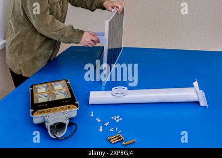 Mounting bracket for attaching solar panel and led street light to pole or wall, woman prepared parts for assembly. Stock Photo