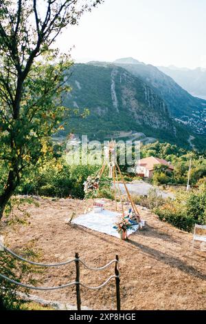 Wedding arch-wigwam with a blanket and bouquets of flowers stands on the mountain Stock Photo
