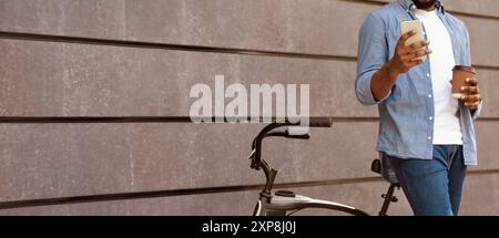 Unrecognizable man with bicycle using smartphone and drinking coffee outdoors Stock Photo