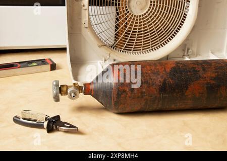 Freon cylinder and disassembled air conditioner on the floor in the apartment, repair and refilling of the air conditioner Stock Photo