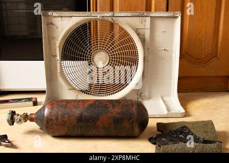 Freon cylinder and disassembled air conditioner on the floor in the apartment, repair and refilling of the air conditioner Stock Photo