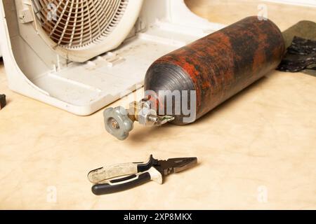 Freon cylinder and disassembled air conditioner on the floor in the apartment, repair and refilling of the air conditioner Stock Photo