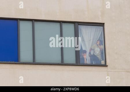 Rotherham, UK. 04 AUG, 2024. Persons housed in the hotel look out of the Windows towards the crowd  as hundreds of police and protestors clash outside a Holiday Inn Express on Manvers way, Rotherham. The right wing demonstrators, described by Sir Kier Starmer as 'thugs' set fire to property, smashed glass and fought with police for several hours. Multiple arrests and Injuries to rioters and police. Credit Milo Chandler/Alamy Live News Stock Photo