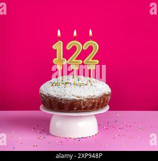 Lighted birthday candle number 122 - Birthday card on pink background Stock Photo