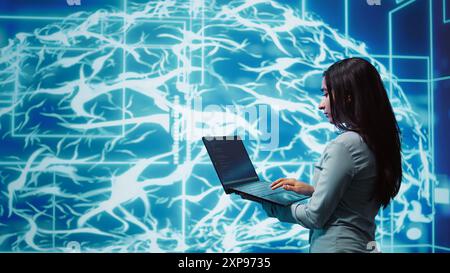 Computer scientist working on laptop, programming artificial intelligence computing simulating human brain. Woman using notebook, developing AI machine learning algorithms, camera B Stock Photo