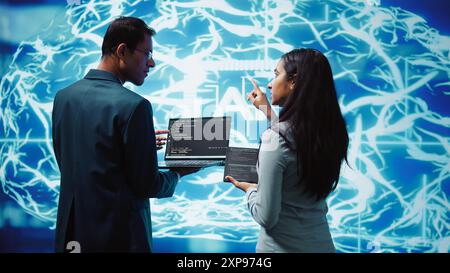 Programmers using devices and AI neural networks modeled after human brain to solve complex problems. Workers using artificial intelligence deep learning to look at data and complete tasks, camera B Stock Photo