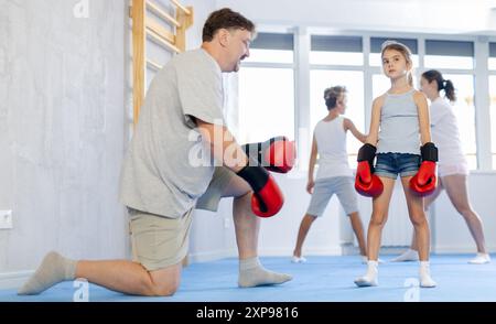 Man sparring with preteen daughter wearing boxing gloves in gym Stock Photo