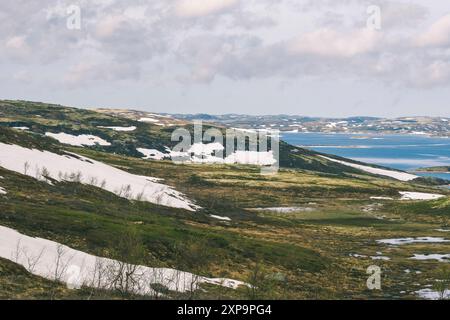 Serene Snow Patches on Rolling Hills by Tranquil Lake during Spring. Teriberka, Russia Stock Photo