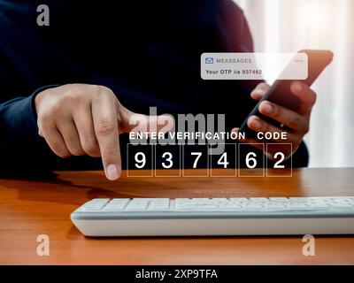 2FA or two factor authentication, cyber security concept. Password code number for enter verification code showing on computer while man hold smartpho Stock Photo