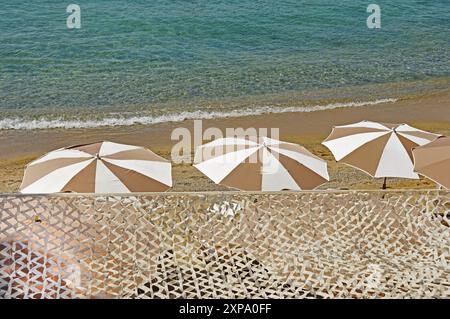 Four umbrellas on the beach against the background of waves Stock Photo