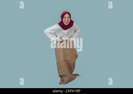 Excited Indonesian woman wearing a hijab and gunny sack to join competition for Indonesian Independence Day celebration. Stock Photo