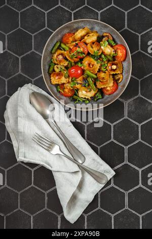 Overhead view of fried ravioli stuffed with meat served with string beans, tomato and mushrooms Stock Photo