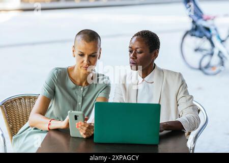 Two professional women working outdoors with technology Stock Photo