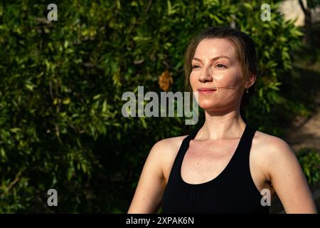 A pretty young woman with reddish hair in close up, doing her yoga and Pilates routine in the sunshine. Stock Photo