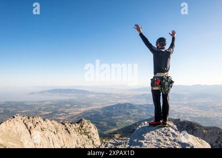 Climber standing on mountaintop with raised arms, Salt Lake City, Utah, USA Stock Photo