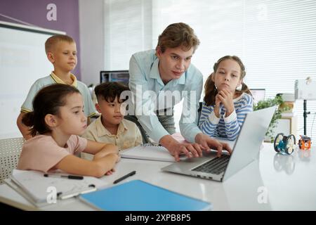 Teacher Guiding Children on Laptop in Classroom Setting Stock Photo