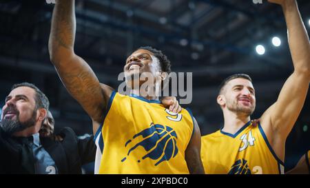 Happy Diverse Sports Team Victorious at Basketball Association Playoffs: Group of Players Celebrate the Victory Together with a Coach. Close Up Portrait on Live Sports Broadcast Television Channel Stock Photo