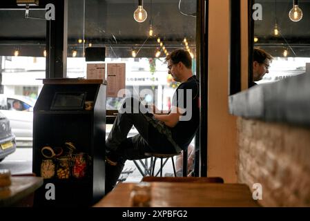 Man sitting in cafe window seat Stock Photo