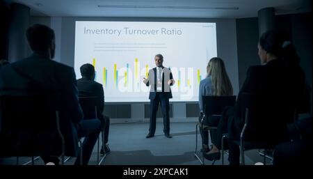 Corporate Event: Caucasian Male Tech CEO Giving Presentation To Colleagues or Investors In the Conference Room Of Innovative Startup Office. Man Talking About Business Objectives and Improving Profits Stock Photo