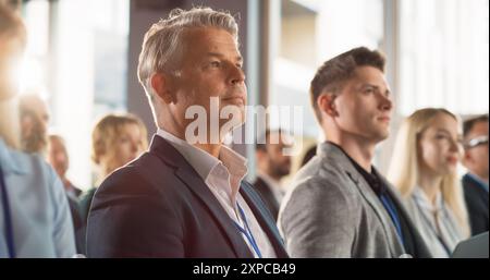 Close Up Of Caucasian Man Sitting in Crowded Audience at Business Conference And Using Laptop. Company Delegate Watching Entrepreneurship Presentation About Developing Markets, Financial Opportunities Stock Photo