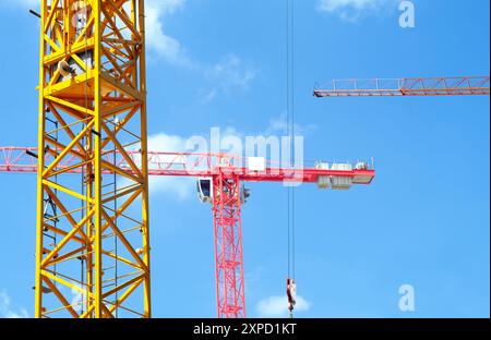 tower cranes building large office buildings against blue sky with clouds Stock Photo