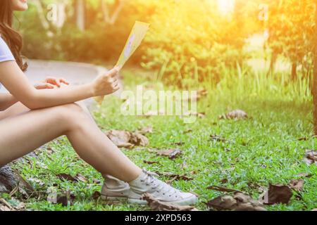 A young female traveler is sitting on the edge of the road to see the map and the destination she wants to go on. The girl sat alone on the roadside i Stock Photo