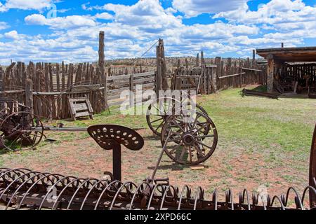 Antique farm equipment in rustic picket fenced yard Stock Photo