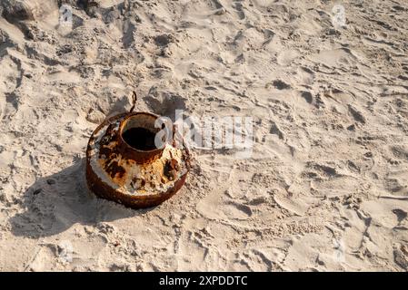 Old and rusty aluminium milk container thrown by the sea and found on the beach represents coastal pollution Stock Photo