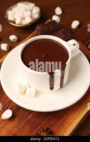 Tasty melted chocolate in cup and marshmallows on wooden table Stock Photo