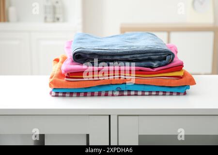 Stack of clean clothes on white dresser indoors Stock Photo
