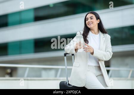 Woman in White Suit Using Phone at Airport Stock Photo