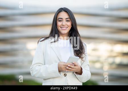 Young Woman Using Smartphone in Front of Modern Building Stock Photo