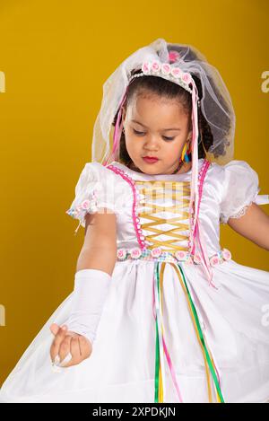 Portrait of a girl in a wedding dress, cheerful, beautiful and smiling, outgoing, posing for the camera. Isolated on yellow background. Stock Photo