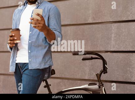 Unrecognizable man with bicycle using smartphone and drinking coffee outdoors Stock Photo
