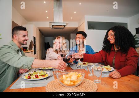 Multiracial group of friends toasting with wine glasses during a fun meal. Two multicultural couples having a good time while enjoying drinks and making a toast at a friendly celebration at home. High quality photo Stock Photo
