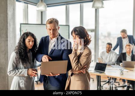 Business Professionals Discussing Project Details on Laptop in Modern Office Stock Photo