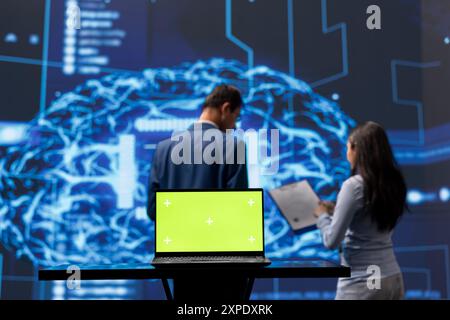 Focus on green screen laptop used by teamworking AI technicians in blurry background using for data analysis. IT experts work on mockup notebook to automatize tasks using artificial intelligence Stock Photo