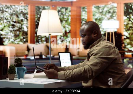 Business owner makes a payment with his card for online shopping at his home, electronic banking to buy resources for his startup. Entrepreneur purchasing something on laptop. Stock Photo