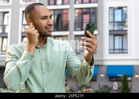 Attractive man using smartphone for online communication by video call in city Stock Photo