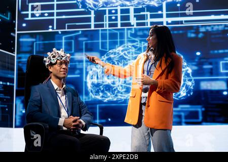 Cognitive experts speaking at neuroscience tech expo, exploring latest AI technology trends. Data researchers presenting latest EEH headset and artificial intelligence innovations during large event Stock Photo