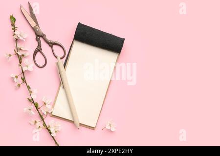 Composition with blooming tree branch, notebook, pencil and scissors on pink background Stock Photo